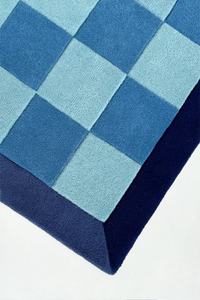 square blue checkered rug with a geometric pattern on a white background