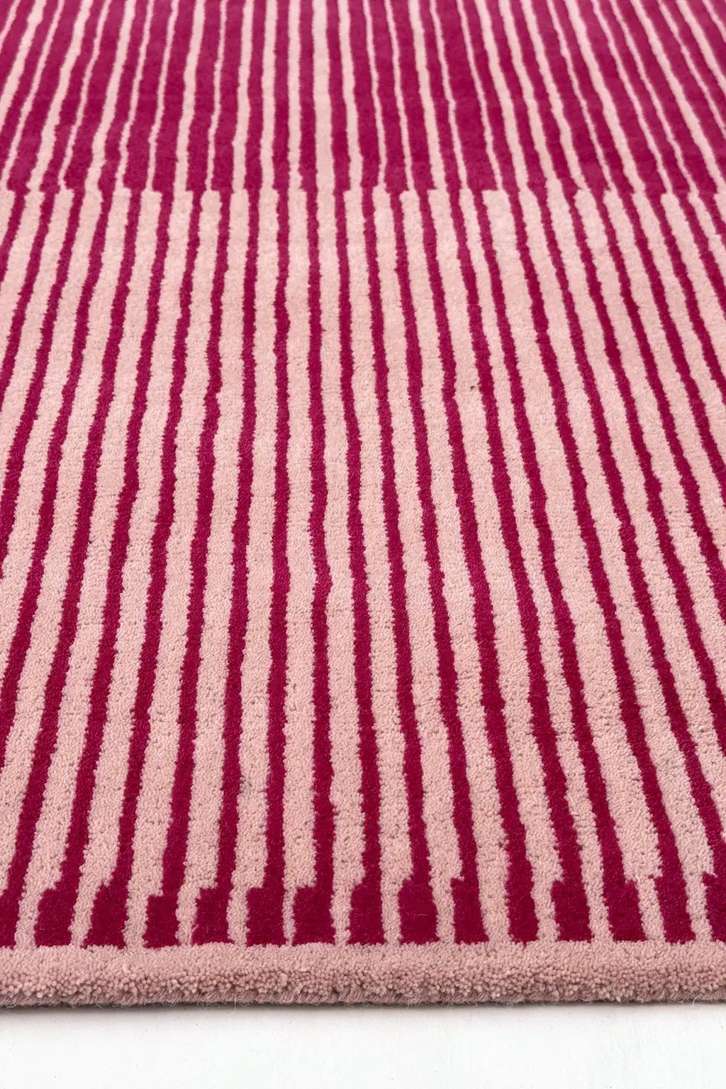 Rug with pink and beige striped pattern on a white background