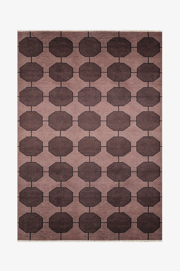 dark brown patterned rug with geometric design on a plain background