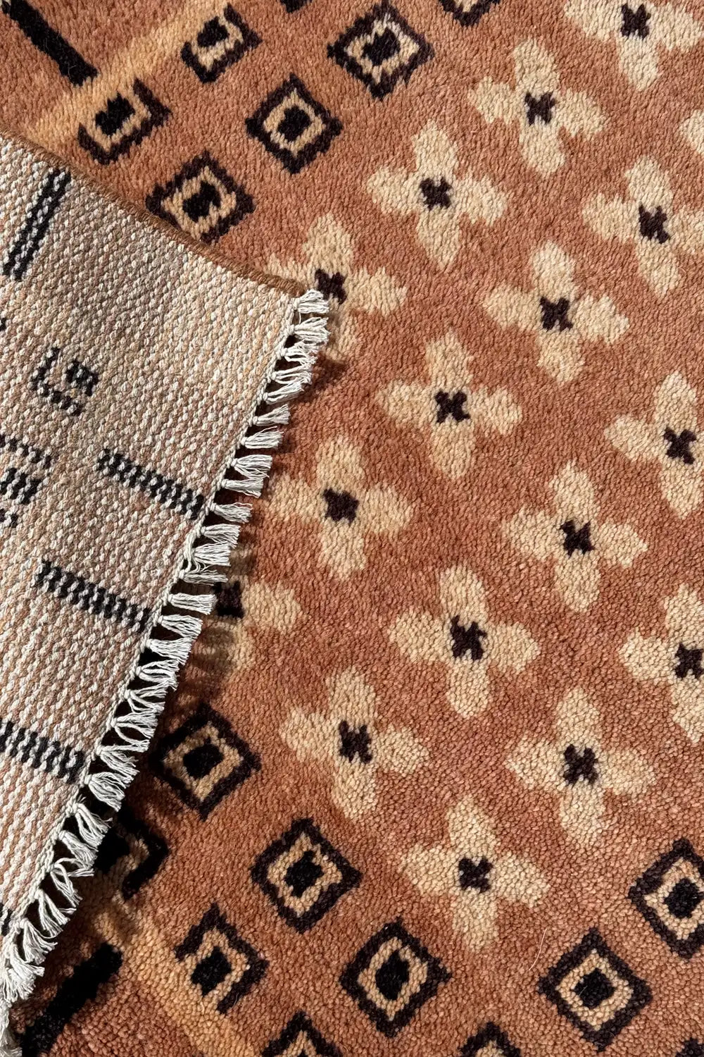 Corner detail of hand knotted wool rug with cream fringe and mid-century inspired geometric patterns