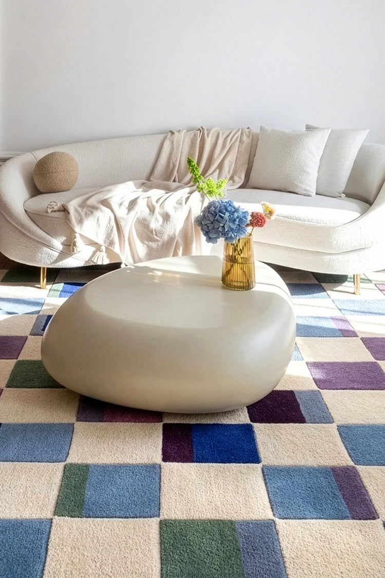Modern living room with a white sofa, coffee table, and colorful rug.