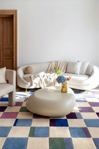 Modern living room with a colorful checkered rug, white sofa, and a small table with flowers lifestyle
