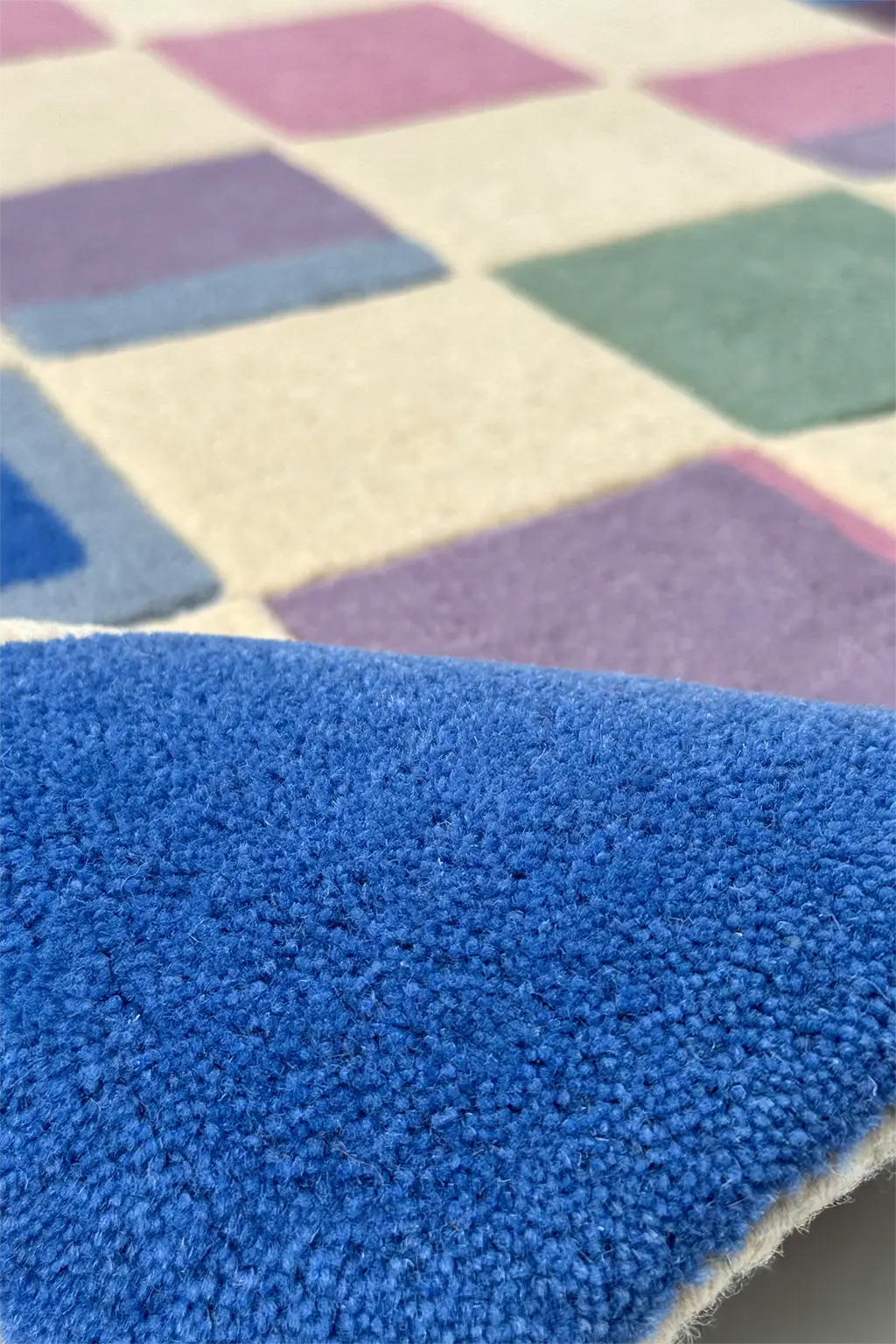 Close-up of a colorful checkered rug with blue, pink, and purple