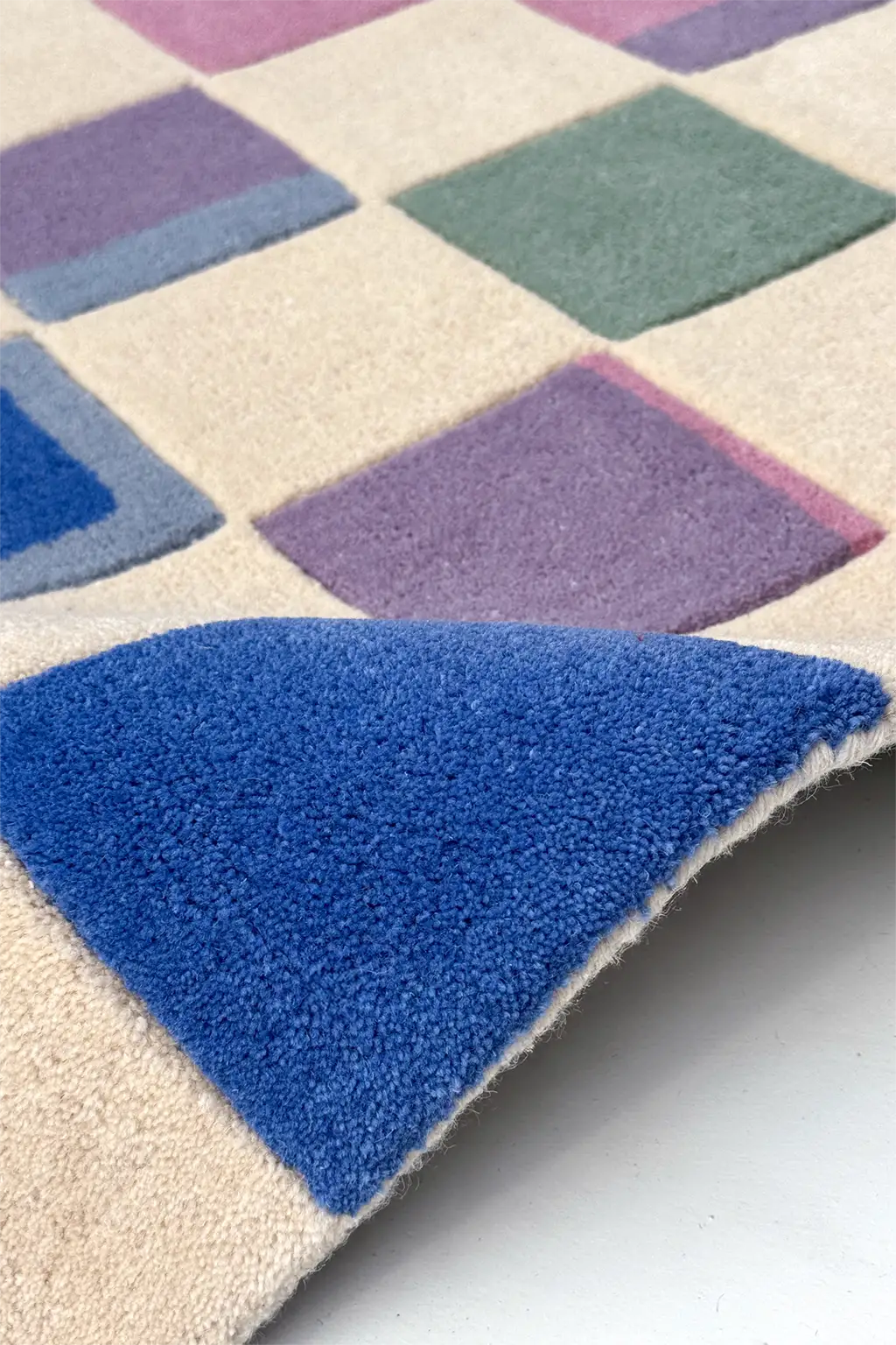 Close-up of a colorful checkered rug with blue, purple, and green squares.