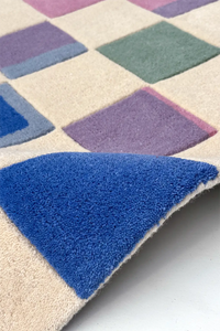 Close-up of a colorful checkered rug with blue, purple, and green squares.