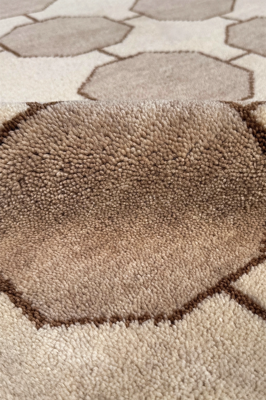 Close-up of a textured ivory cream and beige hand-knotted rug with geometric pattern