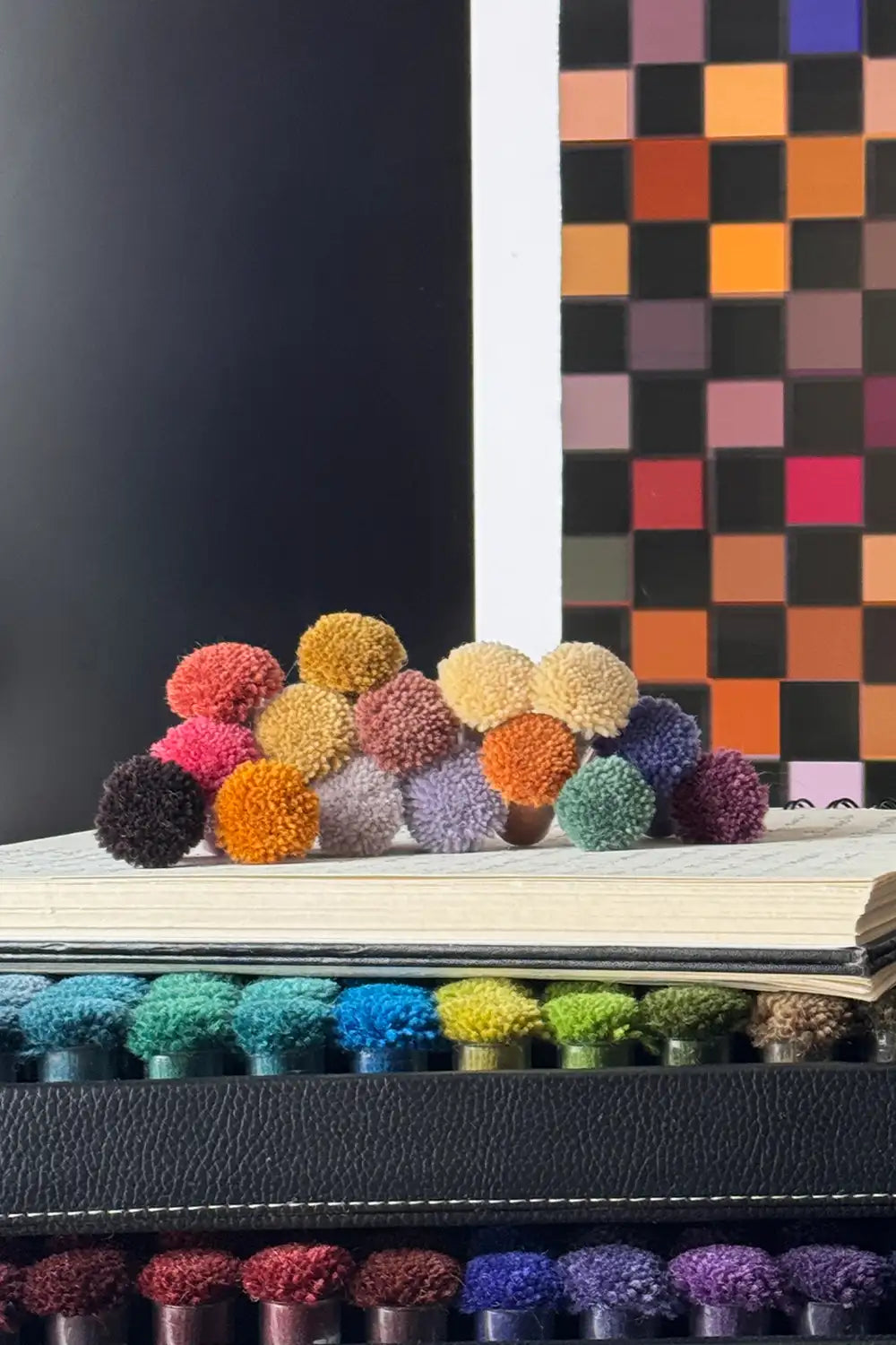 colorful wool poms stacked for a curated palette of a custom checkered rug