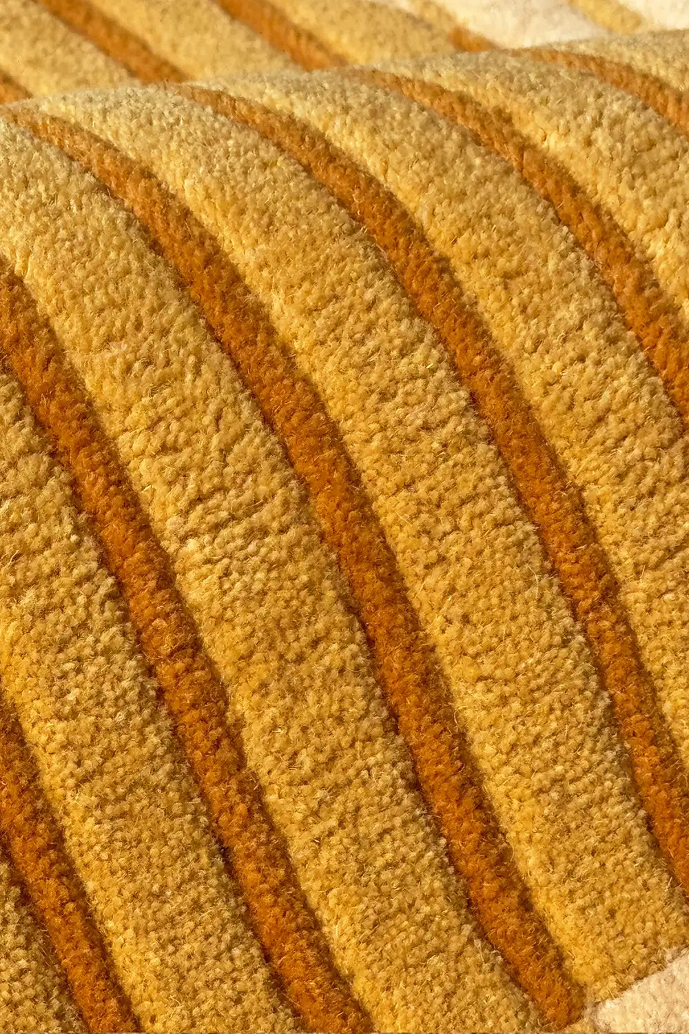 Close-up of a textured yellow and gold round wool rug with modern striped design