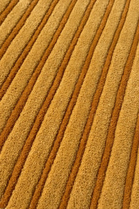 close-up of gold and orange stripes on a modern round wool rug