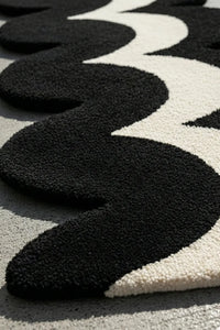 close up view of tufted black and white runner rug with irregular wavy shape