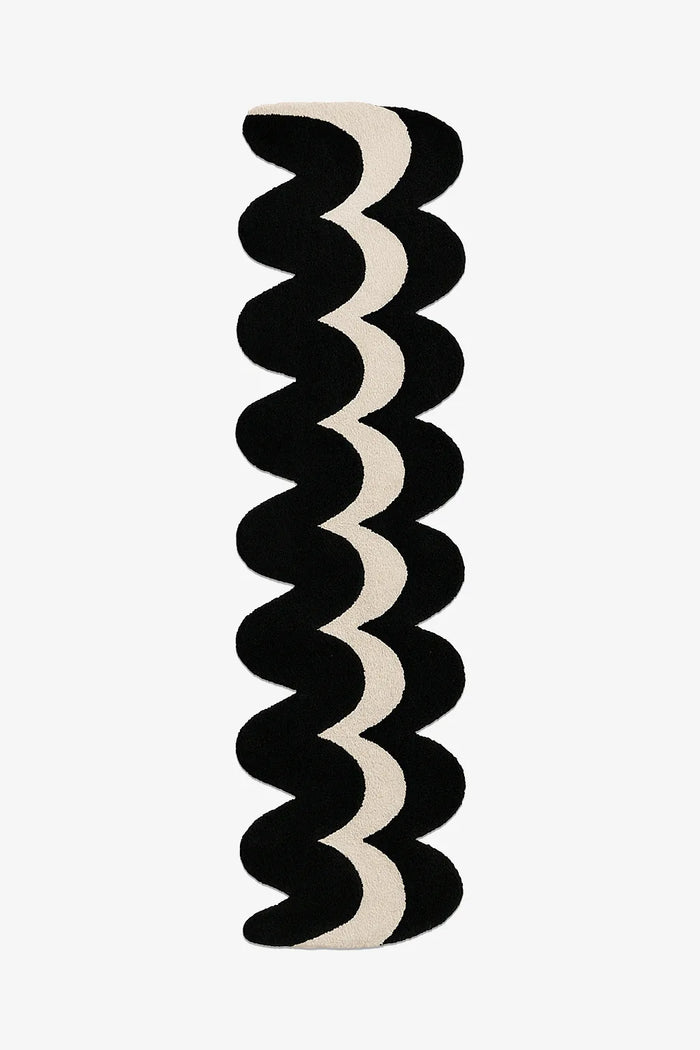 Wavy patterned runner rug with black and white colors on a white background