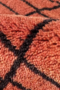 Close-up of a textured rust rug surface with black lines