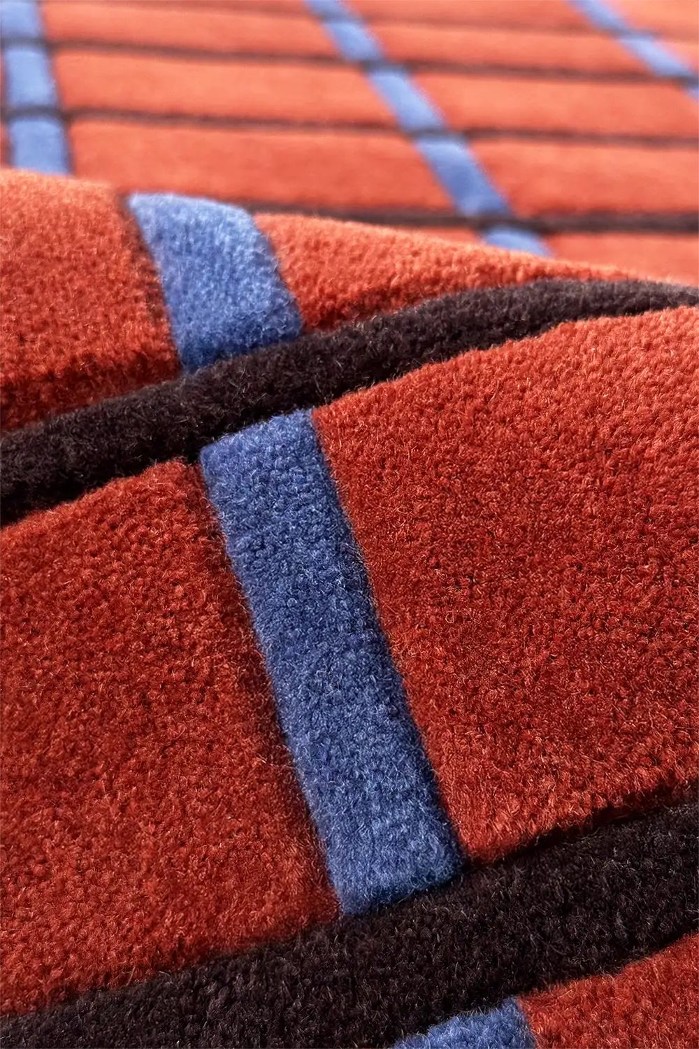 Close-up of a textured wool rug with red, blue, and black plaid pattern