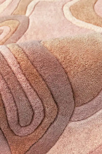 A close-up of a plush, layered area rug with organic, wavy contour lines in shades of rust orange
