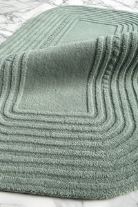 soft sage green textured wool rug on a marble surface