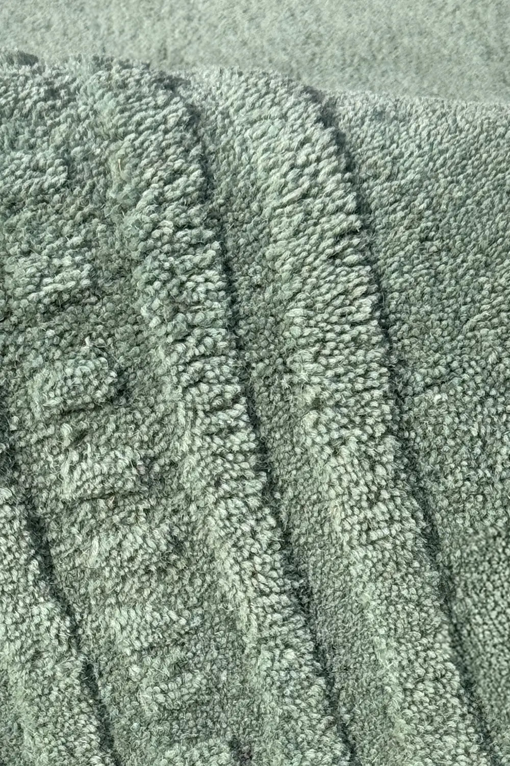 Close-up of textured green wool rug with a subtle pattern