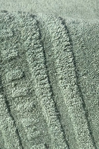 Close-up of textured green wool rug with a subtle pattern