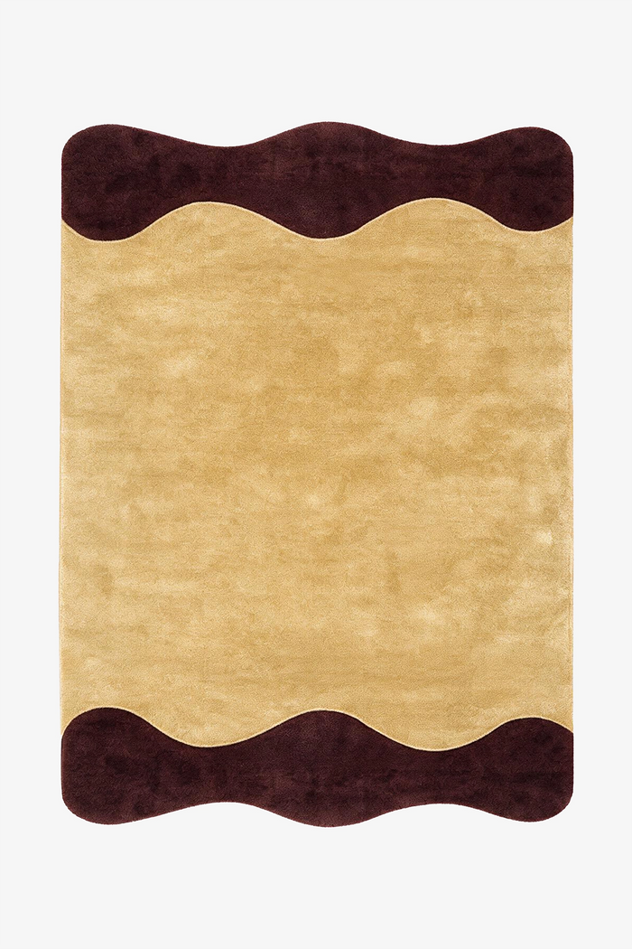 A rectangular area rug with a wavy scalloped border, featuring a textured yellow center and dark brown wavy top and bottom borders, shown flat against a plain white background.