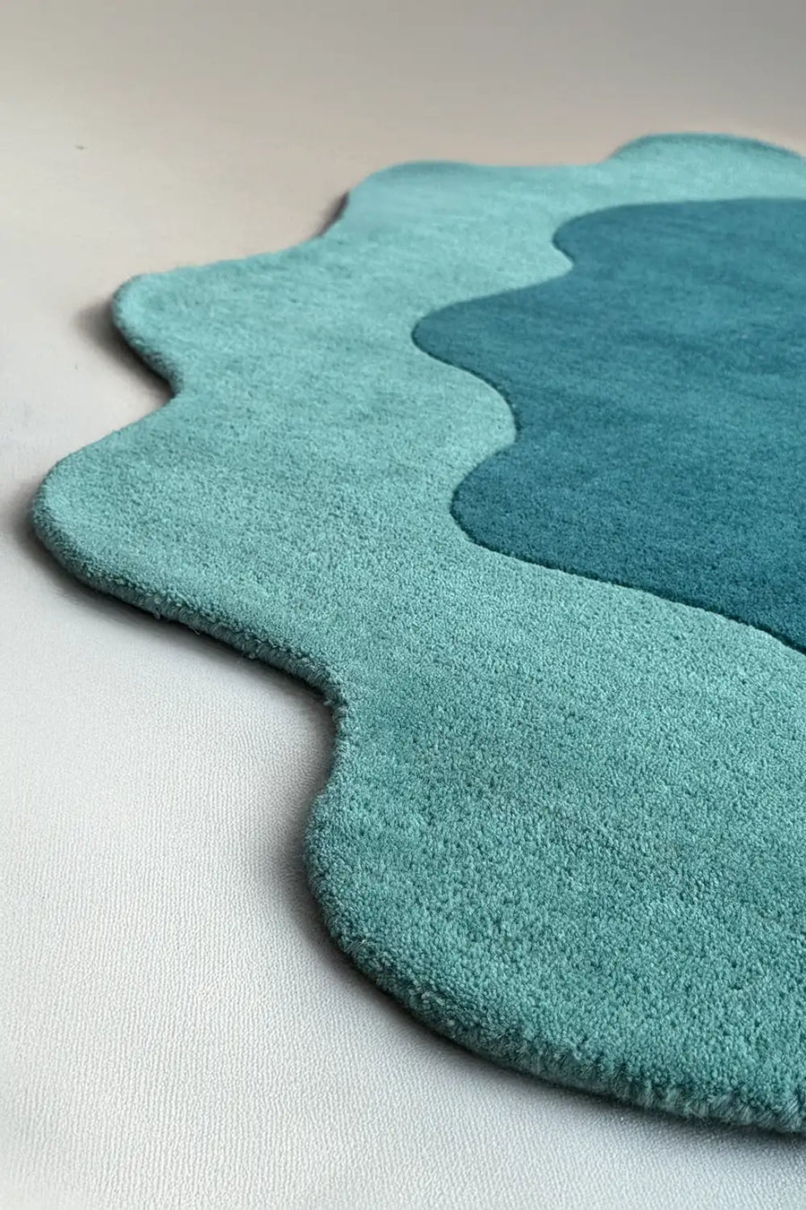Wavy edge detail of teal novelty rug with puddle-like outline, perfect as a unique shaped rug or scalloped area rug for kids’ rooms