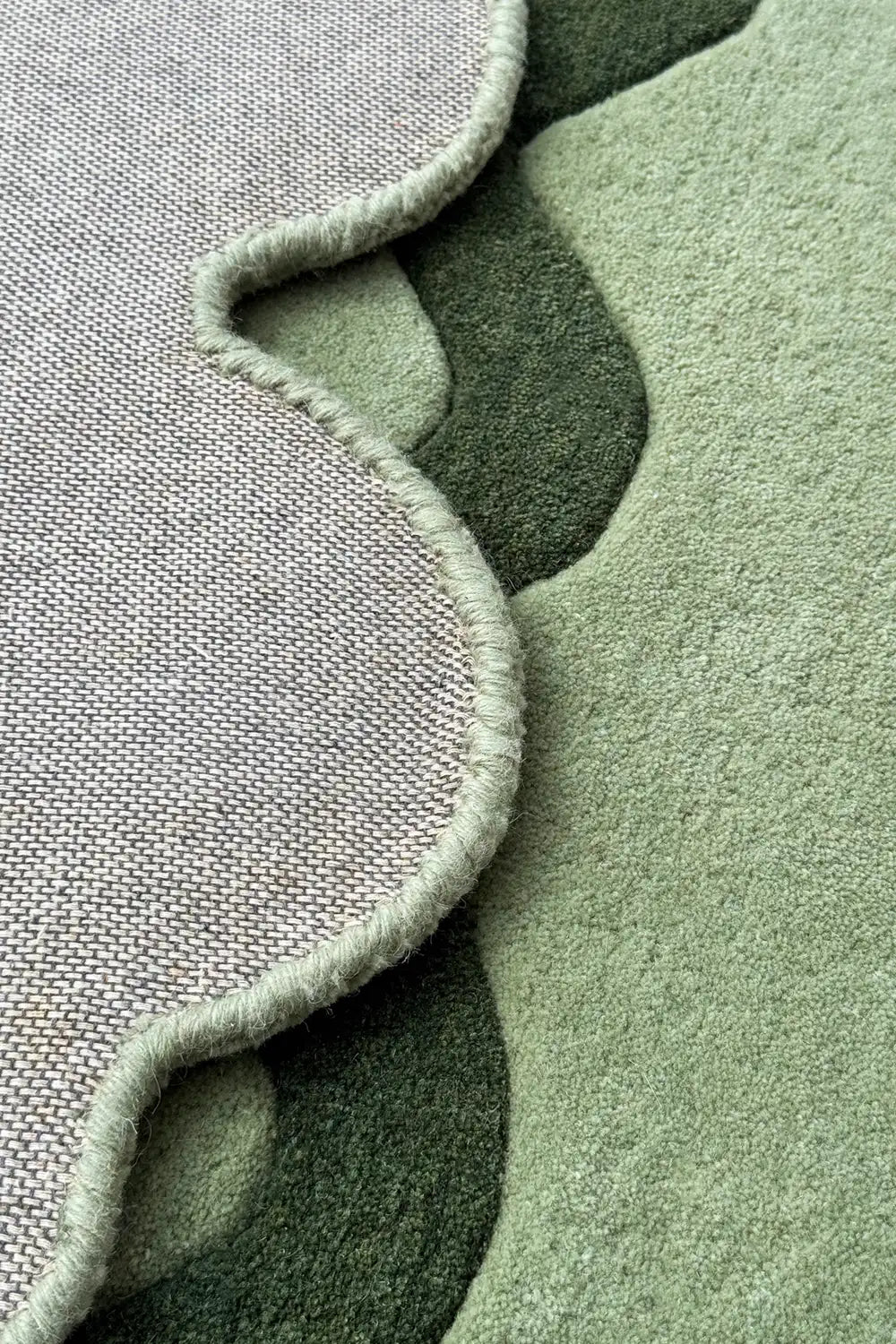 Folded view of scalloped sage green wool rug, handmade boho modern tufted rug