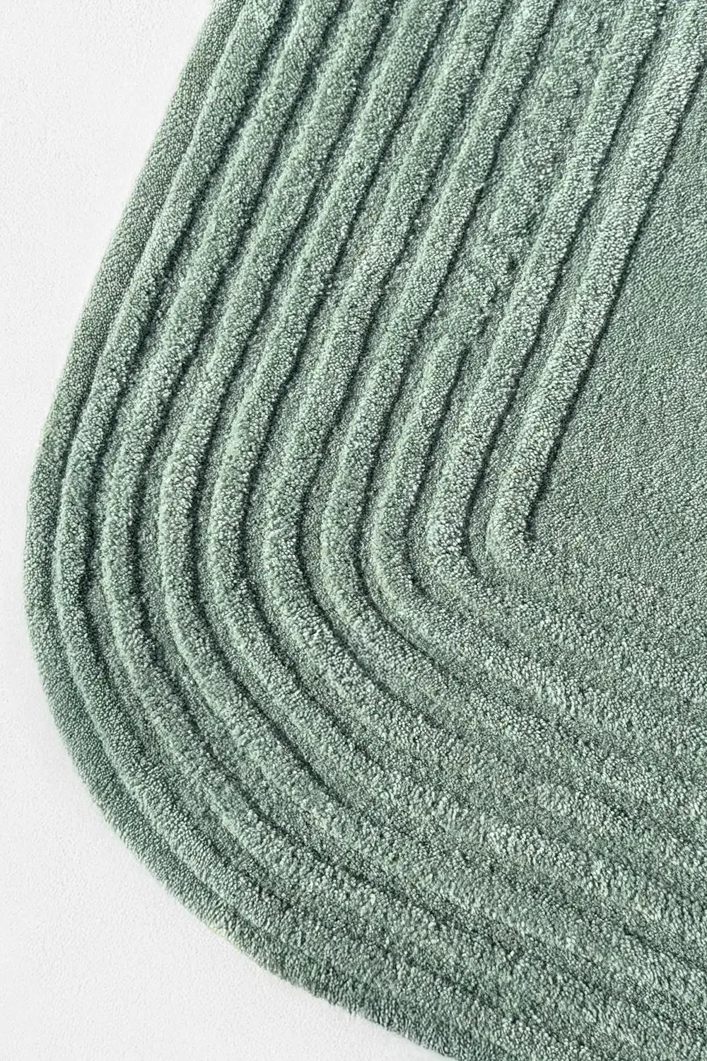 Close-up of oval corner showing layered carved lines in sage green wool, ideal for green room decor or eco-friendly homes