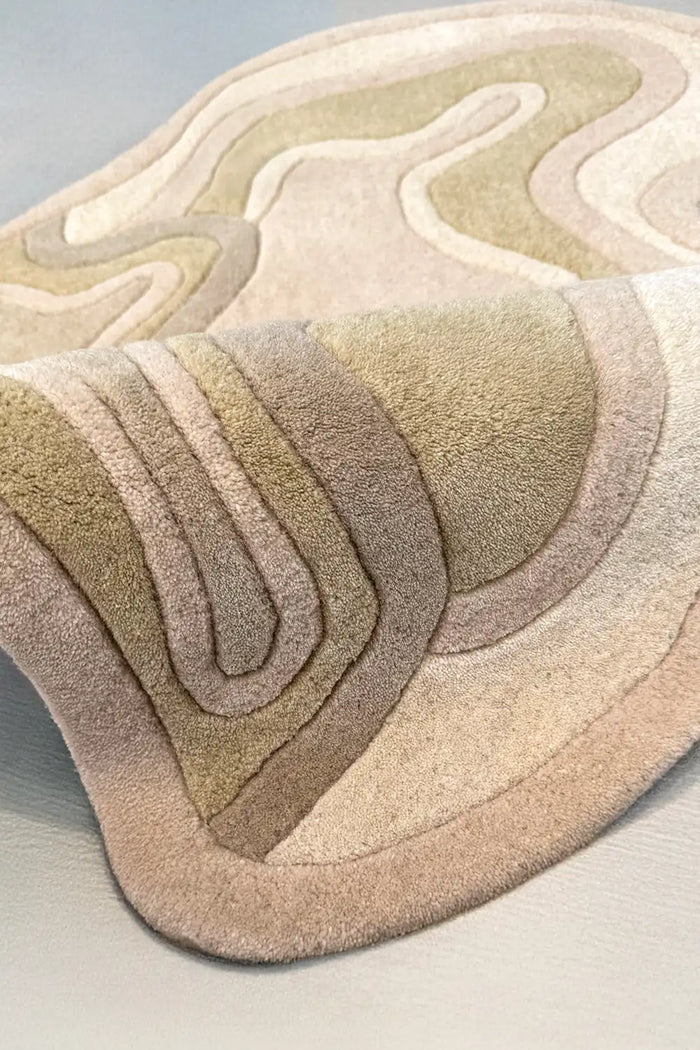 Soft tan tufted wool rug with abstract wavy edges and tonal shading, placed in a serene modern bedroom