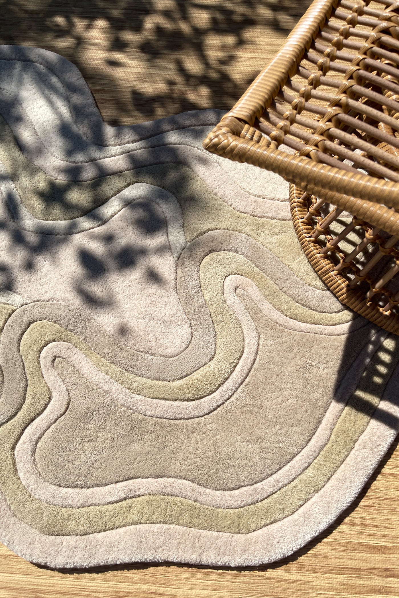 warm tan neutral rug in a sunny boho room with rattan furniture, showcasing the artistic sculpting and plush pile of the rug