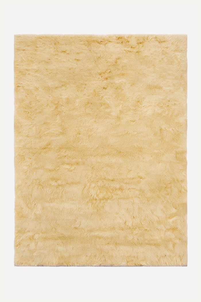 A rectangular shaggy rug in a light pale yellow color, shown flat against a solid white background.
