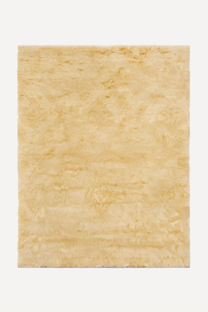 A rectangular pale yellow shag rug with a fluffy, high-pile texture, shown flat against a clean white background.