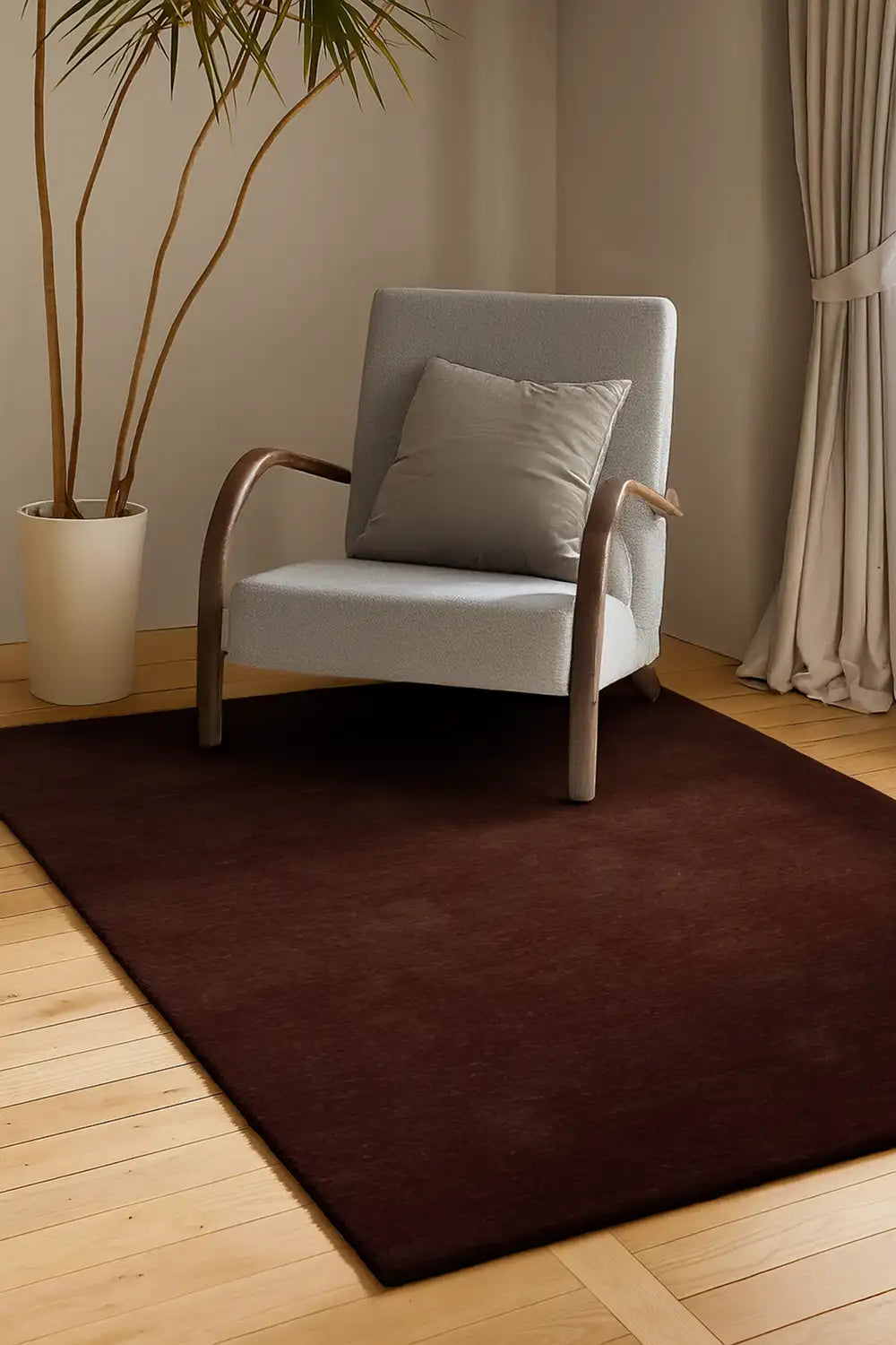 5x8 chocolate brown wool rug in modern living room, shown under armchair on light wood floors with neutral decor

