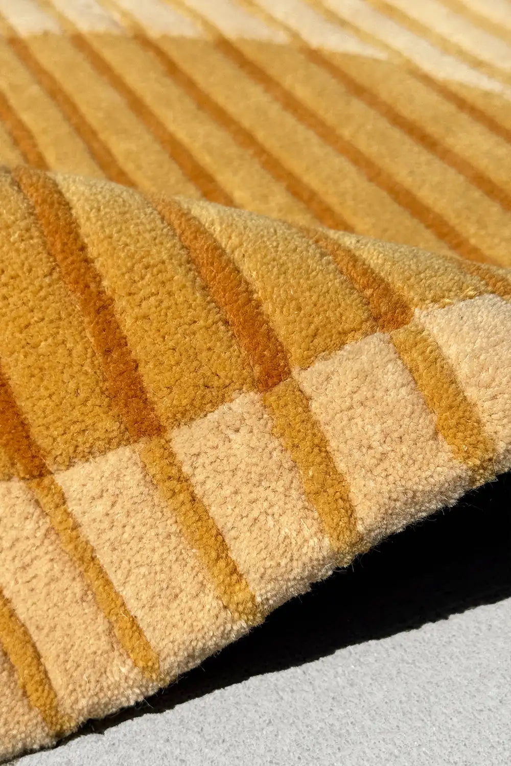 Close-up of a textured yellow and beige rug with striped pattern.