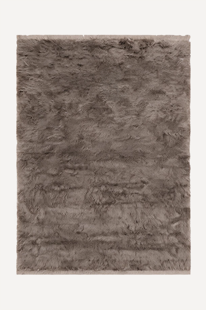 a taupe shag area rug with fringe ends