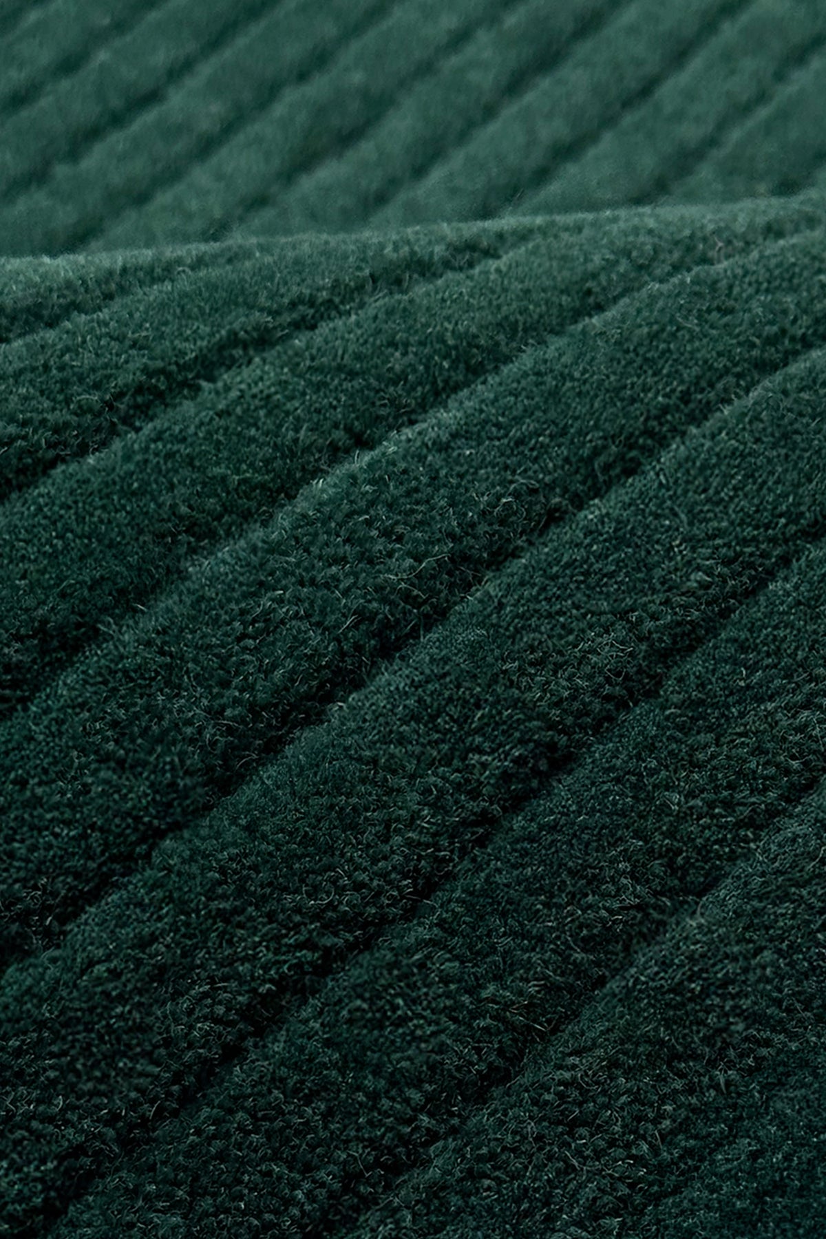 A close-up of dark green ribbed rug texture with diagonal stitched stripes teal
