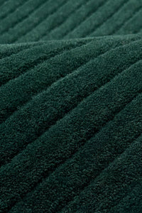 A close-up of dark green ribbed rug texture with diagonal stitched stripes teal