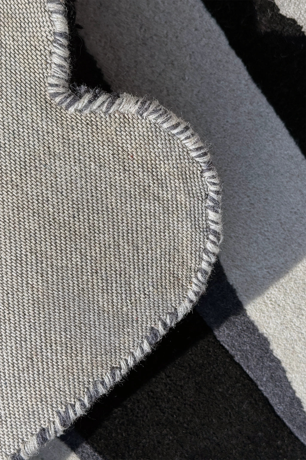close-up of silver rug with scalloped edges and professional binding