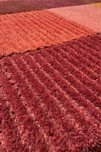 Moody textured wool rug with earthy red and orange tones, boutique handcrafted area rug