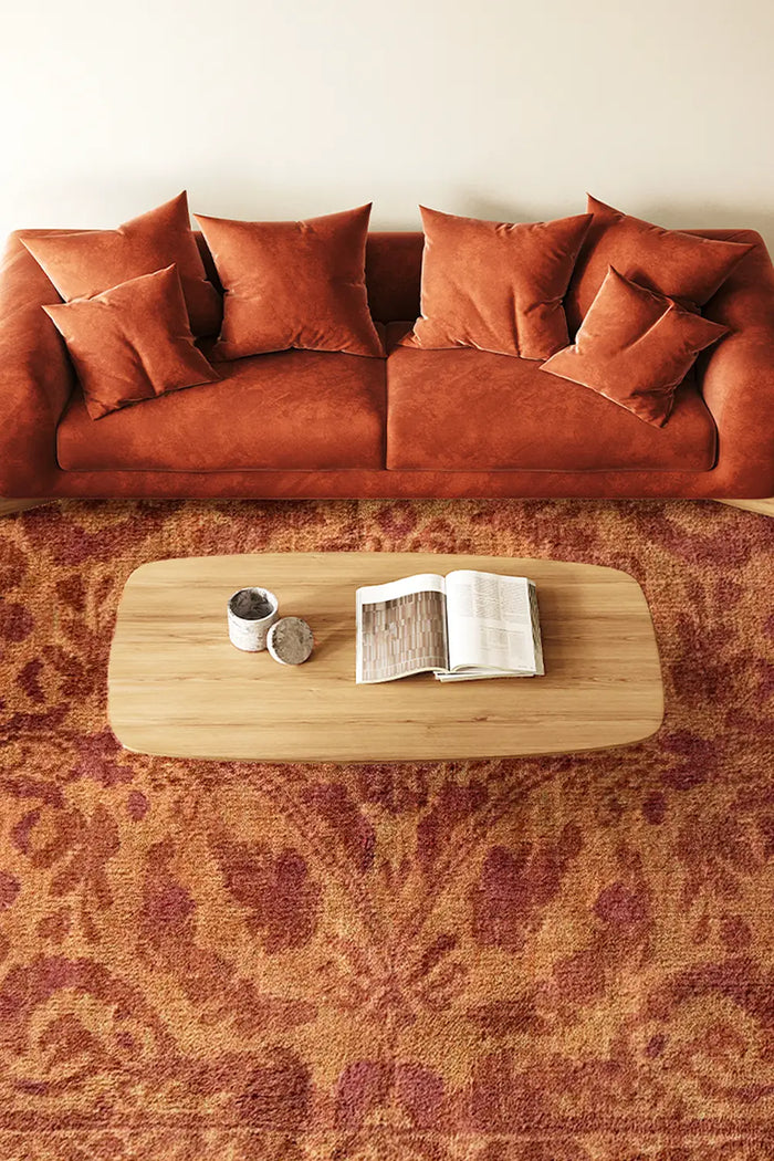 8x10 burnt orange persian rug with traditional floral motifs in a modern living room with rust couch and wood table lifestyle