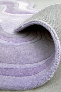 Tufted lavender purple wool rug with ripple-like sculpted texture and soft edge detailing