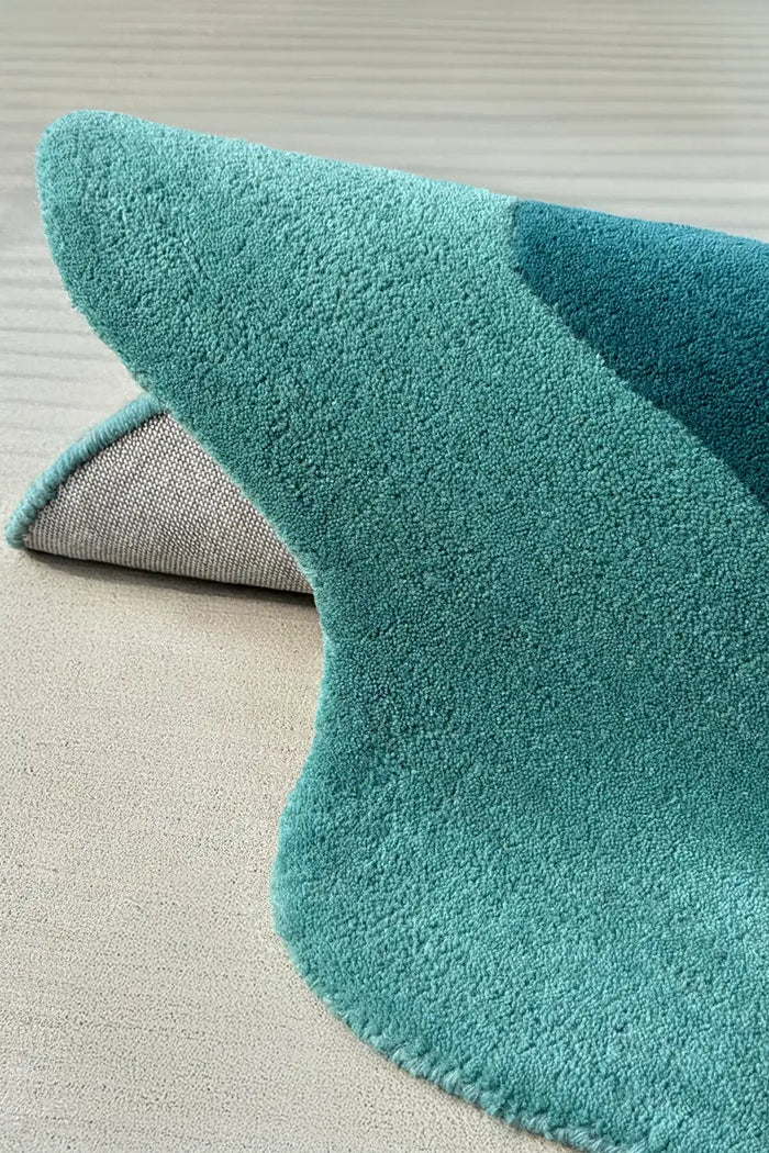 Curved edge detail of turquoise and dark teal scallop rug, a whimsical option for a 6 ft round or oblong shaped rug layout
