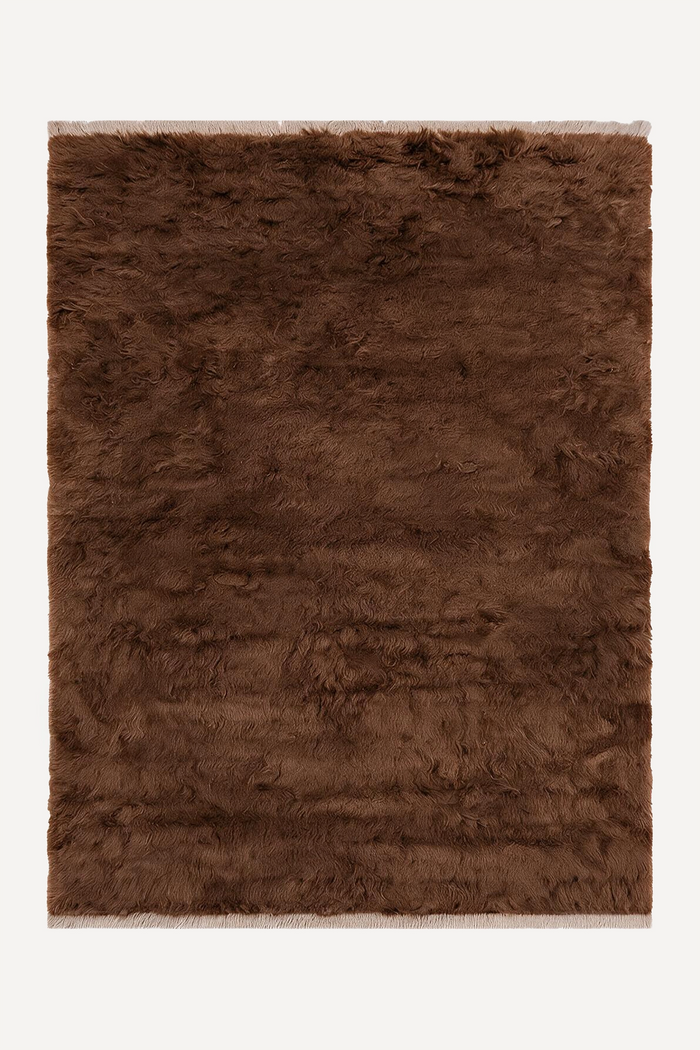 A rectangular umber brown shaggy wool rug with fringed edges, shown flat against a solid white background.