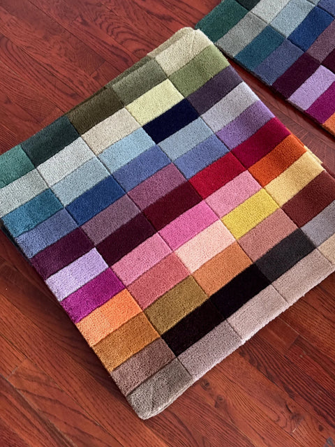 the jubi wool palette, 55 hand-tufted new zealand wool colors, lying on a wood floor
