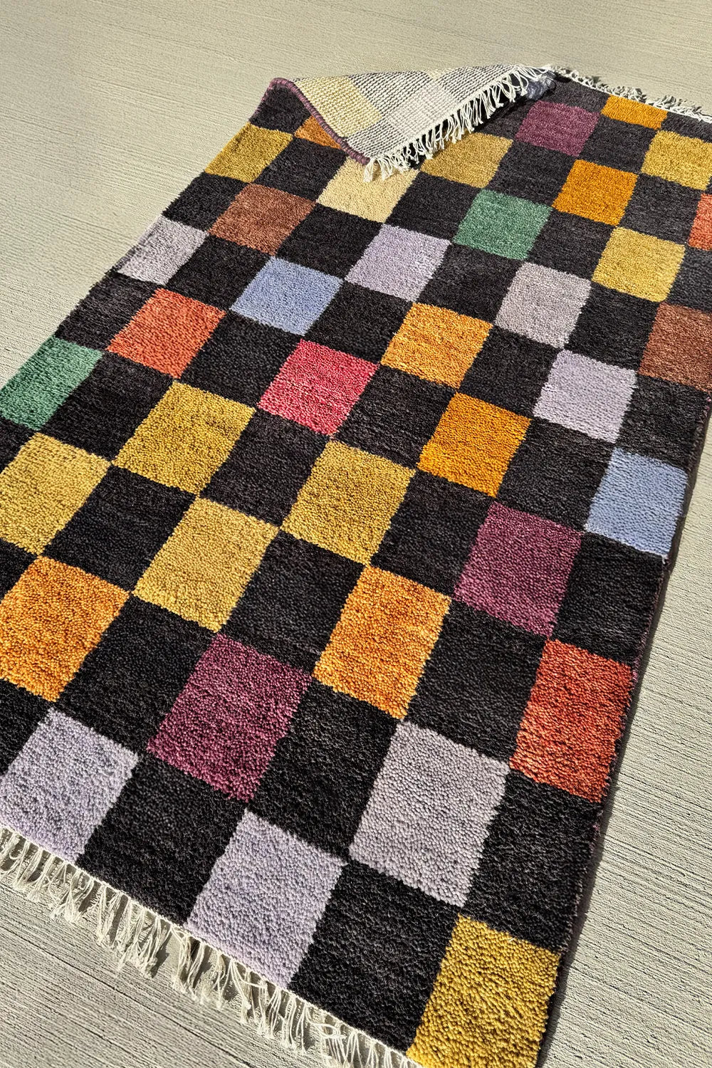 Modern wool rug with a colorful checkered design, crafted by artisans using 100% New Zealand wool.