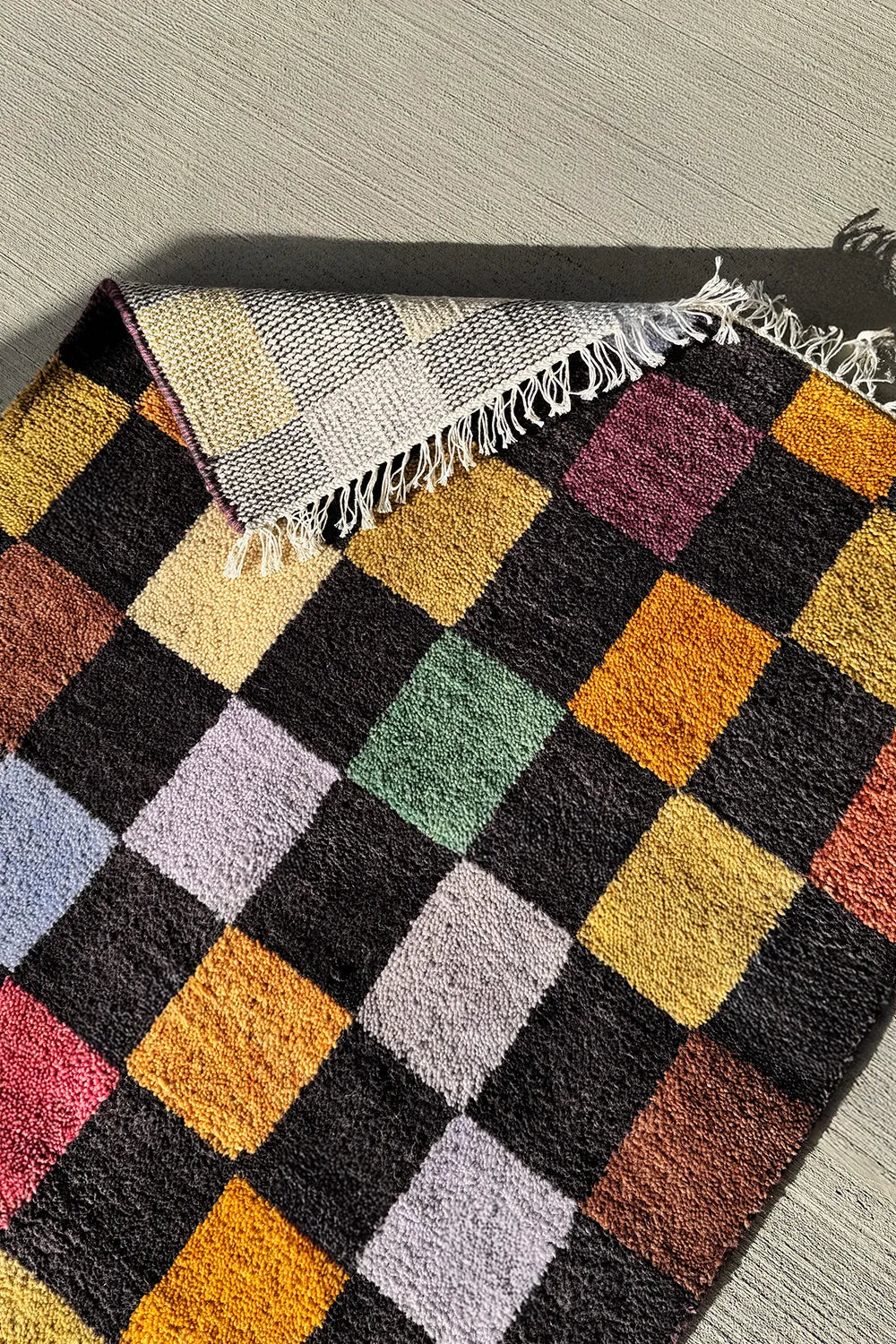 Hand-knotted wool rug with a multicolor checkerboard design and black background