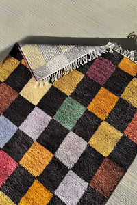 Hand-knotted wool rug with a multicolor checkerboard design and black background