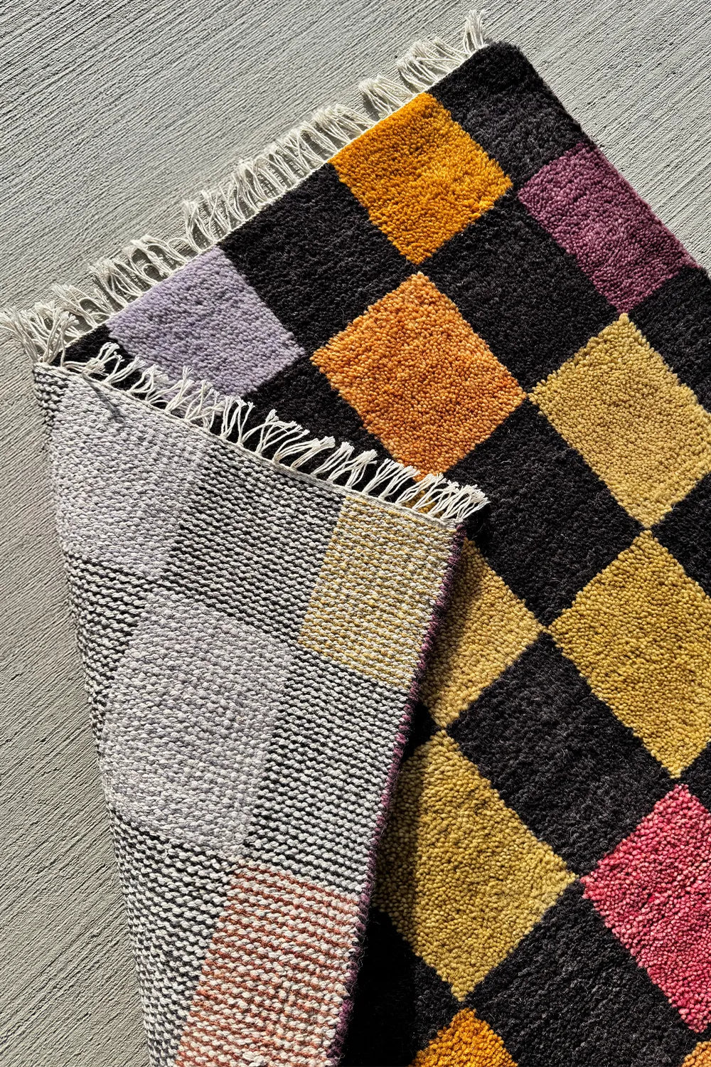 Multicolor checkered area rug with black accents, perfect for living rooms and bedrooms.