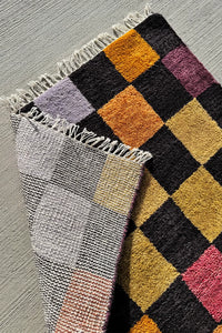 Multicolor checkered area rug with black accents, perfect for living rooms and bedrooms.