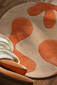 Abstract wool round area rug in orange and beige in a warm, cozy boho bedroom lifestyle