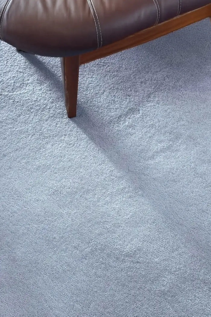 Light baby blue wool rug styled with leather accent chair, perfect for modern living rooms