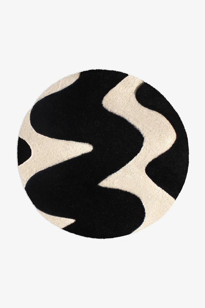 Modern round black and cream wool rug with bold abstract waves, available in 6ft and 8ft sizes