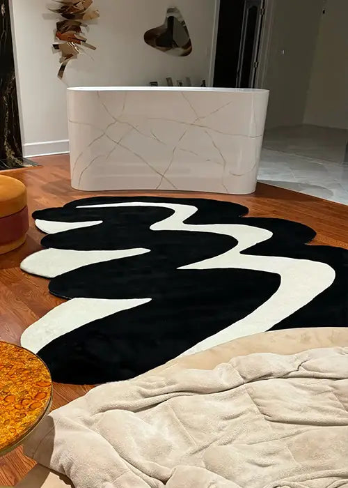 Large black and white wavy rug styled in a luxury modern interior with a sculptural table and warm wood flooring.